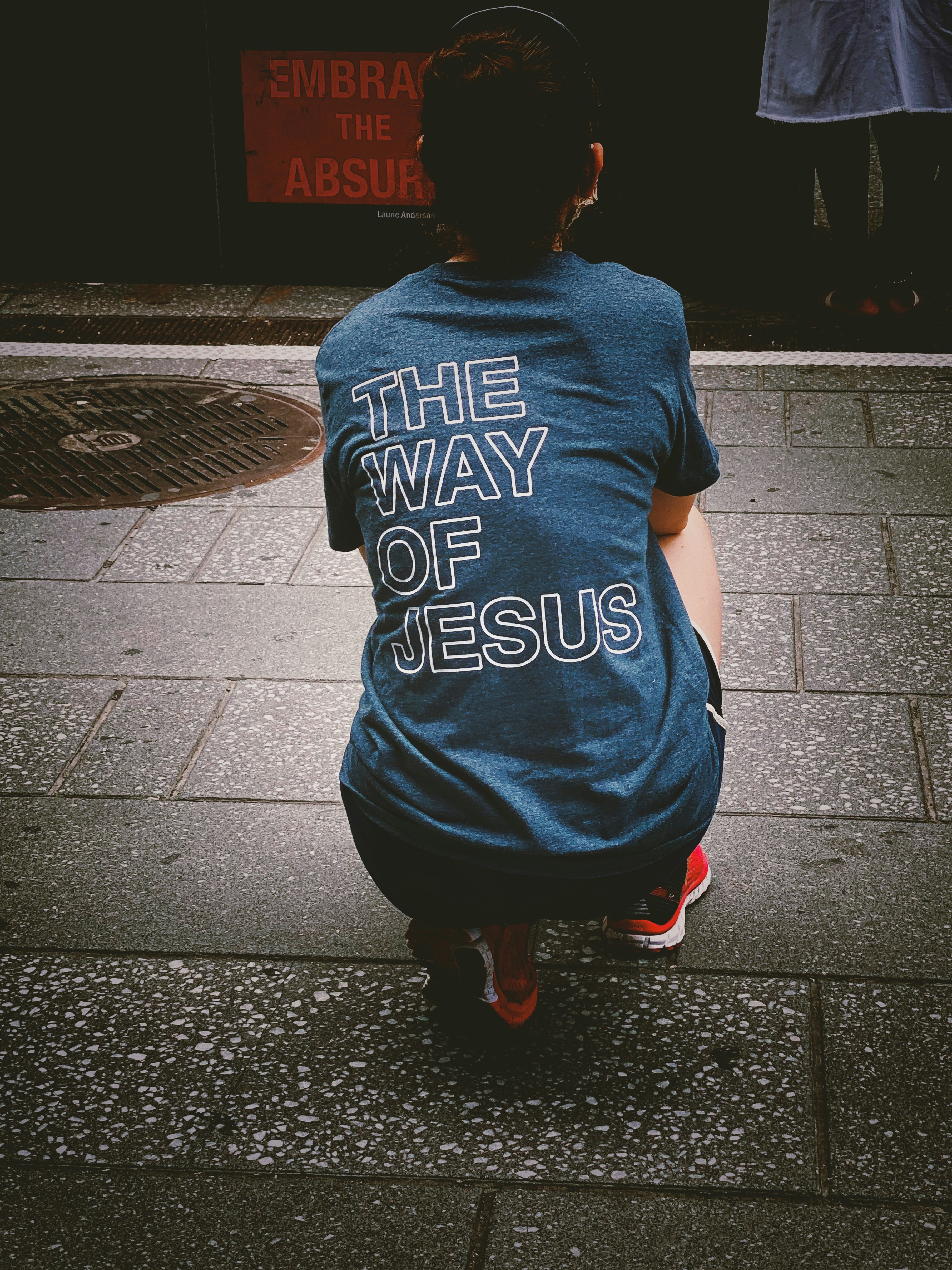 woman in blue and white crew neck t-shirt and black pants standing on gray concrete